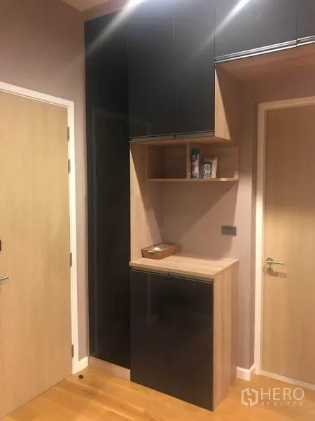 Detached House for rent or sale in Bang Kapi, Bangkok - Hallway storage with black and wood built-in cabinets next to interior doors.