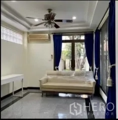 Detached House for rent in Phra Khanong, Bangkok - Bright living room with white sofa, blue curtains, ceiling fan and glossy floor.