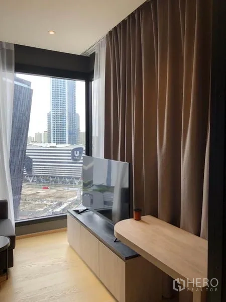 Condominium for rent in Din Daeng, Bangkok - Living room corner with large window, TV console, and city skyline view.