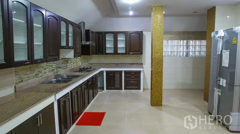 Detached House for rent in Bang Phli, Samut Prakan - Spacious kitchen with dark wood cabinetry, granite counters, tile backsplash and fridge.
