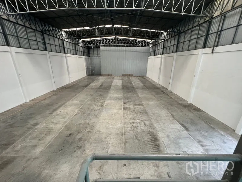 Warehouse for rent in Lat Krabang, Bangkok - Wide storage area with heavy-duty concrete flooring and insulated steel roof, viewed from the mezzanine.