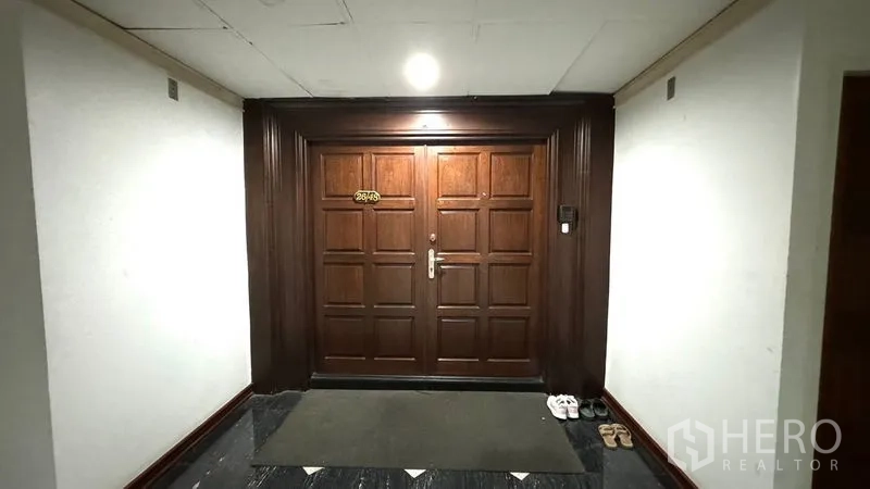 Condominium for rent or sale in Watthana, Bangkok - Entrance corridor with solid wooden double doors to the condominium unit.