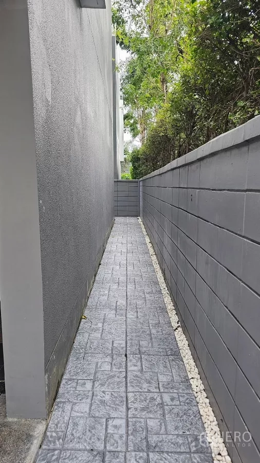 Townhouse for rent in Saphan Sung, Bangkok - Narrow side yard walkway along the corner unit with a privacy wall.