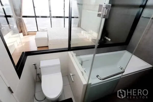 公寓 出租在Khlong San, Bangkok - 现代浴室，带浴缸与观景玻璃，可见卧室与城市景
