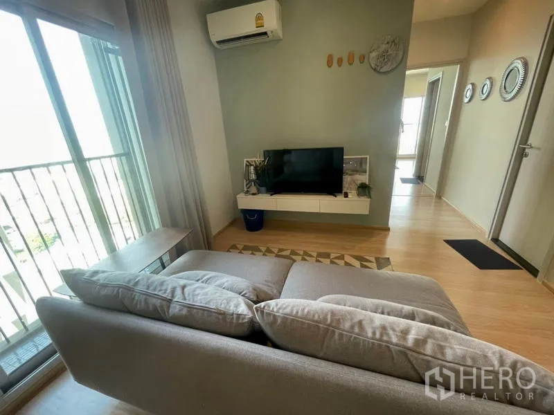 คอนโด ให้เช่าในHuai Khwang, Bangkok - ห้องนั่งเล่นอบอุ่น โซฟาหันหาเคาน์เตอร์ทีวี พร้อมทางออกสู่ระเบียง