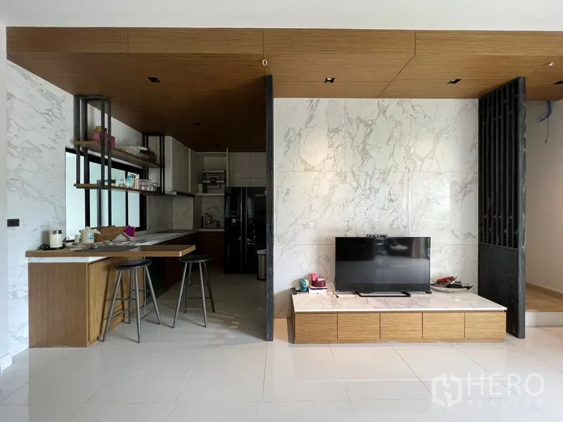Townhouse for rent in Saphan Sung, Bangkok - Open-plan view of kitchen peninsula beside a marble TV wall.