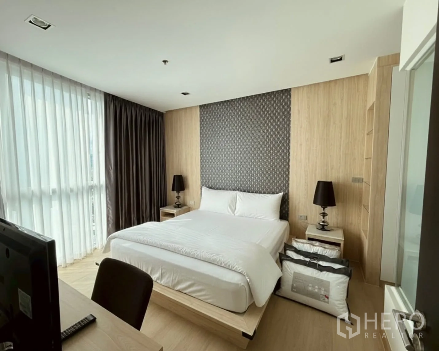 公寓 for rent or sale in Watthana, Bangkok - 卧室采光好，配大床、落地窗、木质墙面与床头灯，旁有书桌。