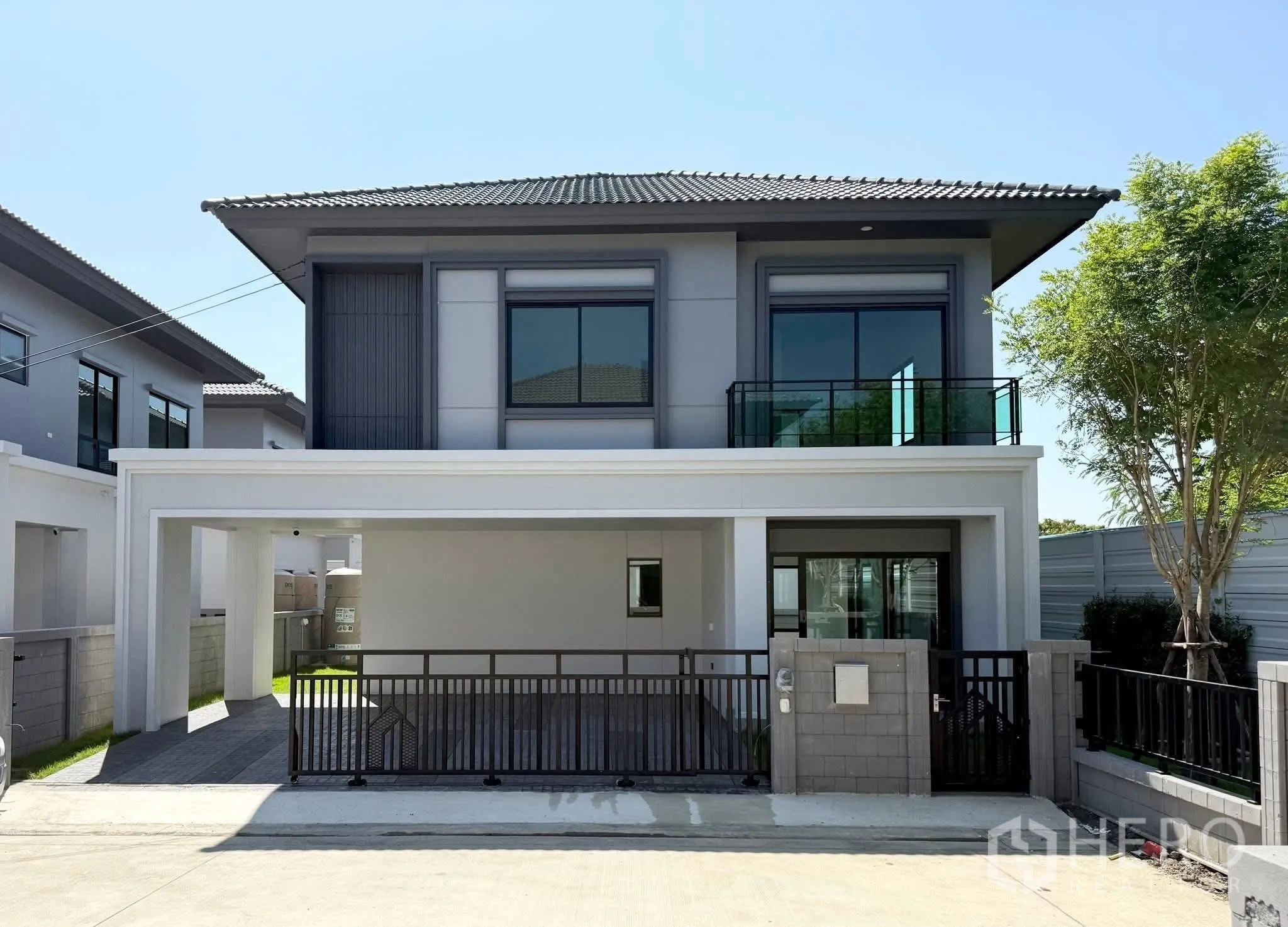 บ้านเดี่ยว for rent in Bang Phli, Samut Prakan - บ้านเดี่ยวสองชั้นสไตล์โมเดิร์น ด้านหน้าเป็นโรงจอดรถมีหลังคาและประตูรั้ว.
