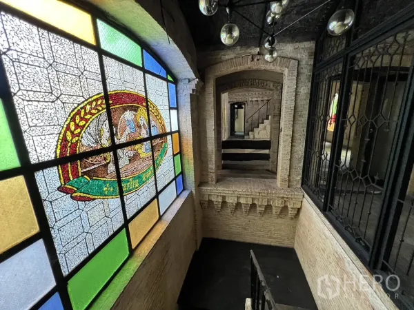 Retail Space for rent in Watthana, Bangkok - Interior corridor featuring a large stained-glass window, exposed brick arches and a stairway.