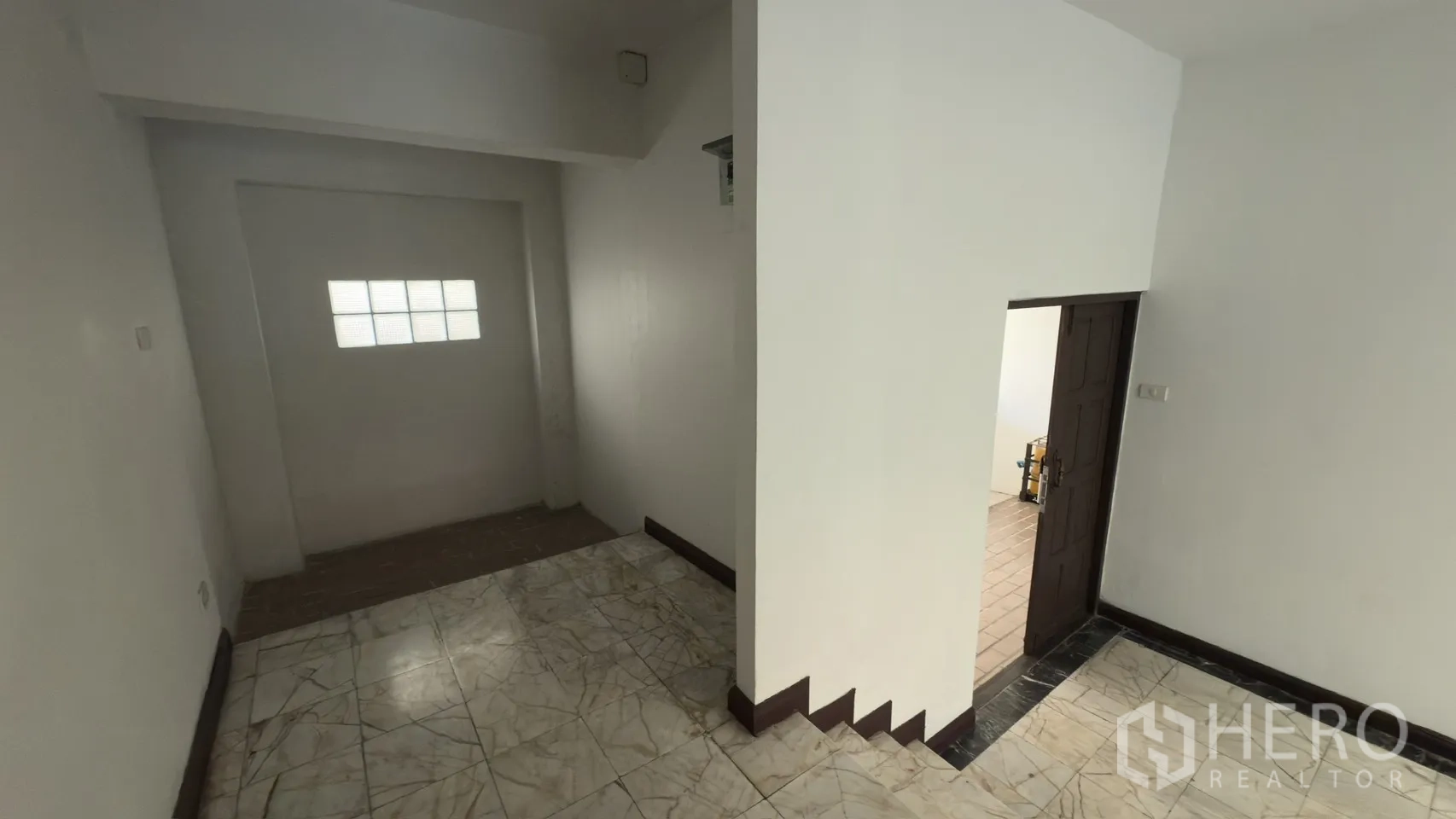 联排别墅 for rent in Watthana, Bangkok - 一层走廊拐角，通往服务区的门与瓷砖地面。