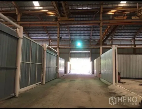Factory for rent in Mueang Samut Prakan, Samut Prakan - Covered loading aisle inside the factory with metal partitions and drive-through access to a roller door.