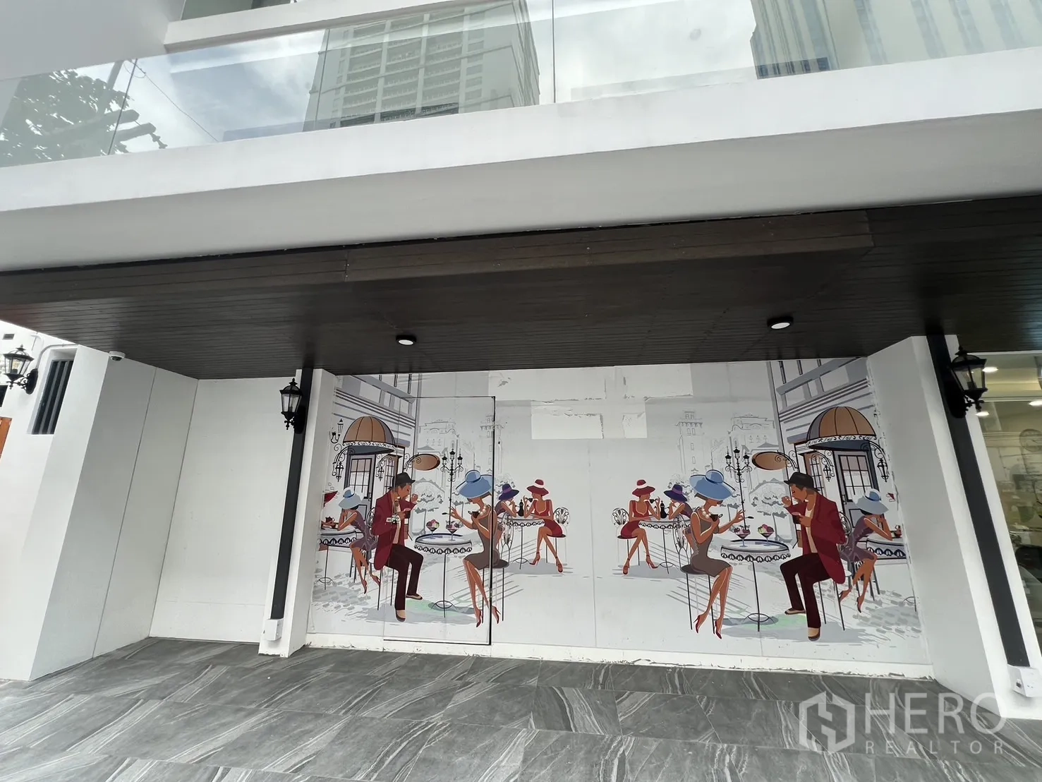 Retail Space for rent - Close-up of shopfront mural beneath a balcony with glass balustrade.