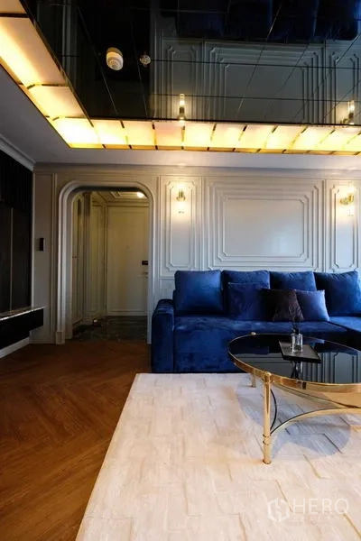 Condominium for sale - Living room with blue sectional sofa and round glass coffee table.