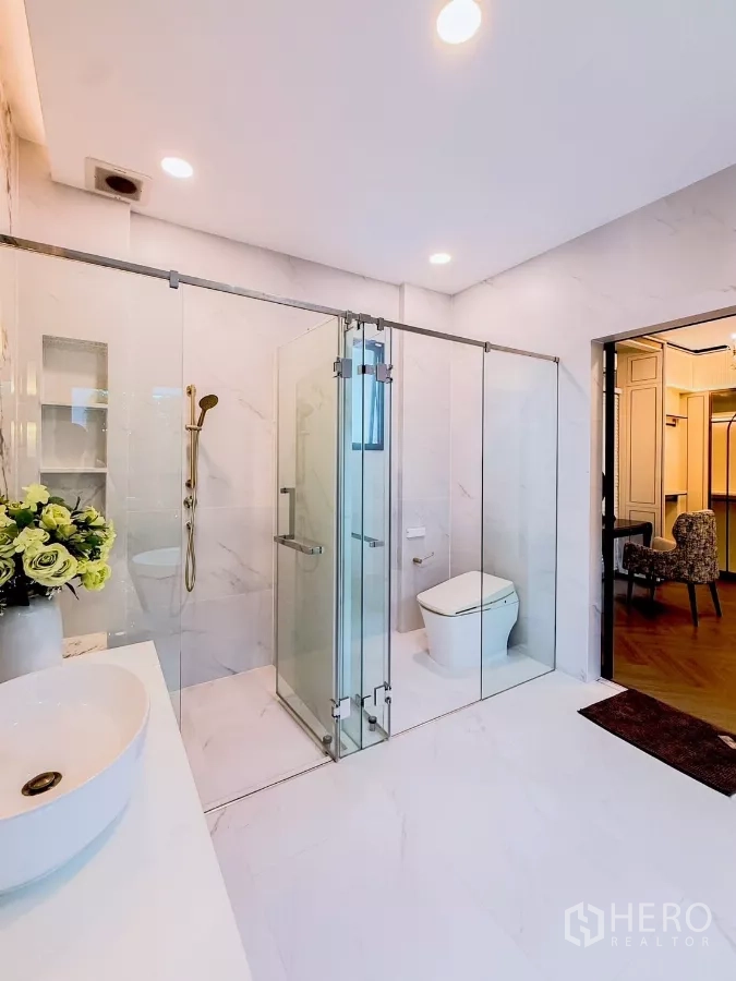 Detached House for rent in Saphan Sung, Bangkok - Bathroom with glass-enclosed shower and toilet in white marble finish.