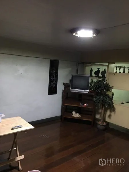 Shophouse for rent in Phra Khanong, Bangkok - Compact living room with wooden flooring, TV stand, and ceiling light.