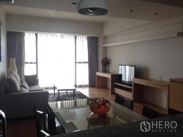Condominium for rent in Sathon, Bangkok - Spacious living room with sofa, TV console, large windows with sheer curtains, and abundant natural light.