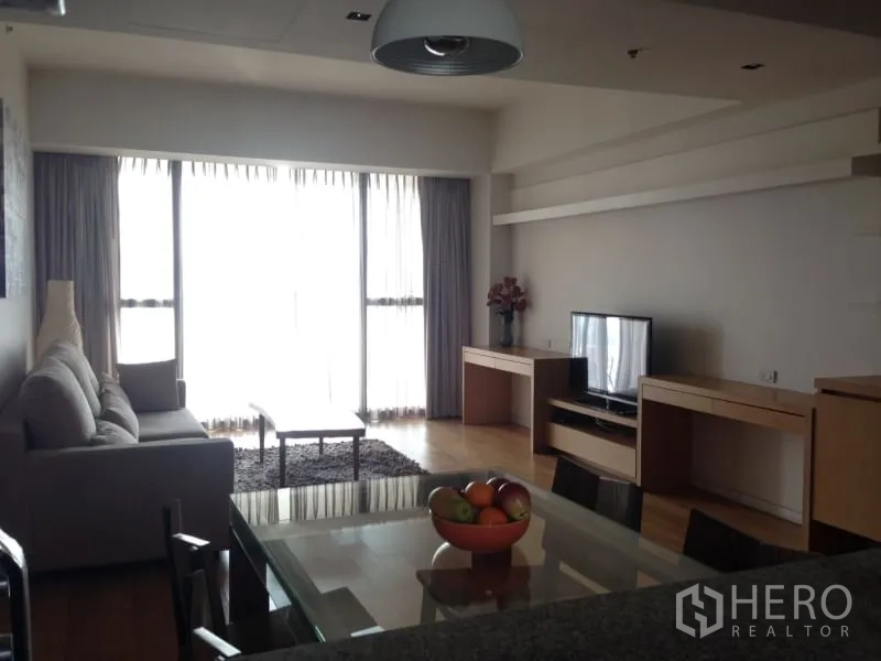 Condominium for rent in Sathon, Bangkok - Spacious living room with sofa, TV console, large windows with sheer curtains, and abundant natural light.