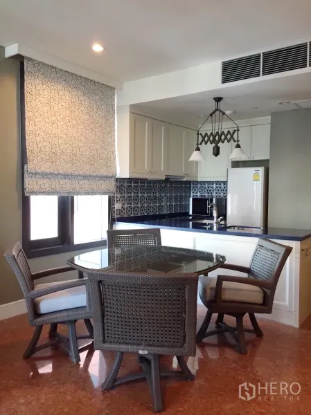 Condominium for rent in Khlong Toei, Bangkok - Khlong Toei condo dining area with wicker table set beside open kitchen and blue counters