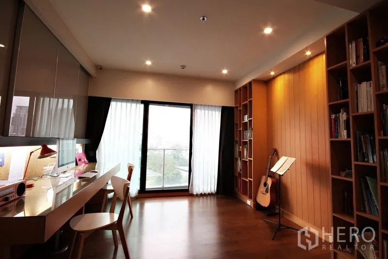 Condominium for rent or sale in Khlong Toei, Bangkok - Spacious multipurpose room with built-in bookshelves, long desk, and balcony.