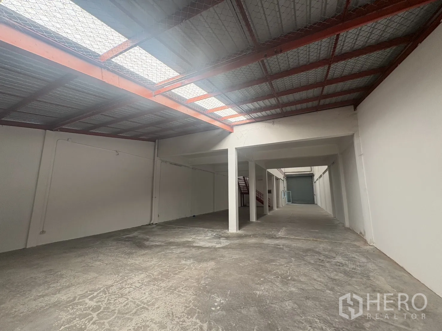 Factory for rent in Phra Samut Chedi, Samut Prakan - Long warehouse bay with skylight panels, support columns and a roller door at the end.