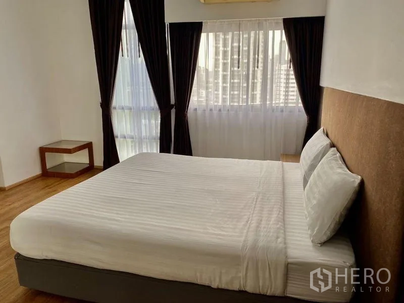 Condominium for rent in Khlong Toei, Bangkok - Master bedroom with king bed, corner windows, sheer curtains and city views over warm wood flooring.