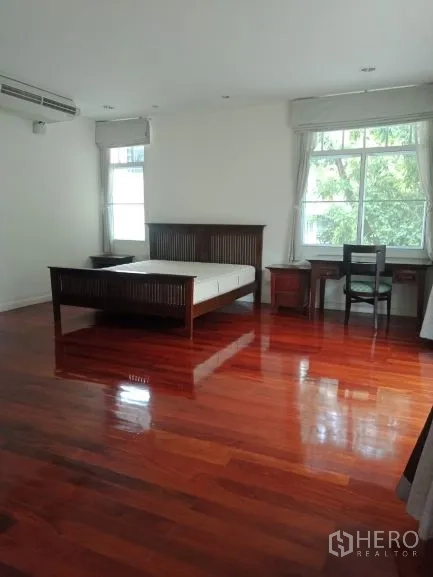 Detached House for rent in Bang Rak, Bangkok - Master bedroom with bed, desk and large windows overlooking greenery.