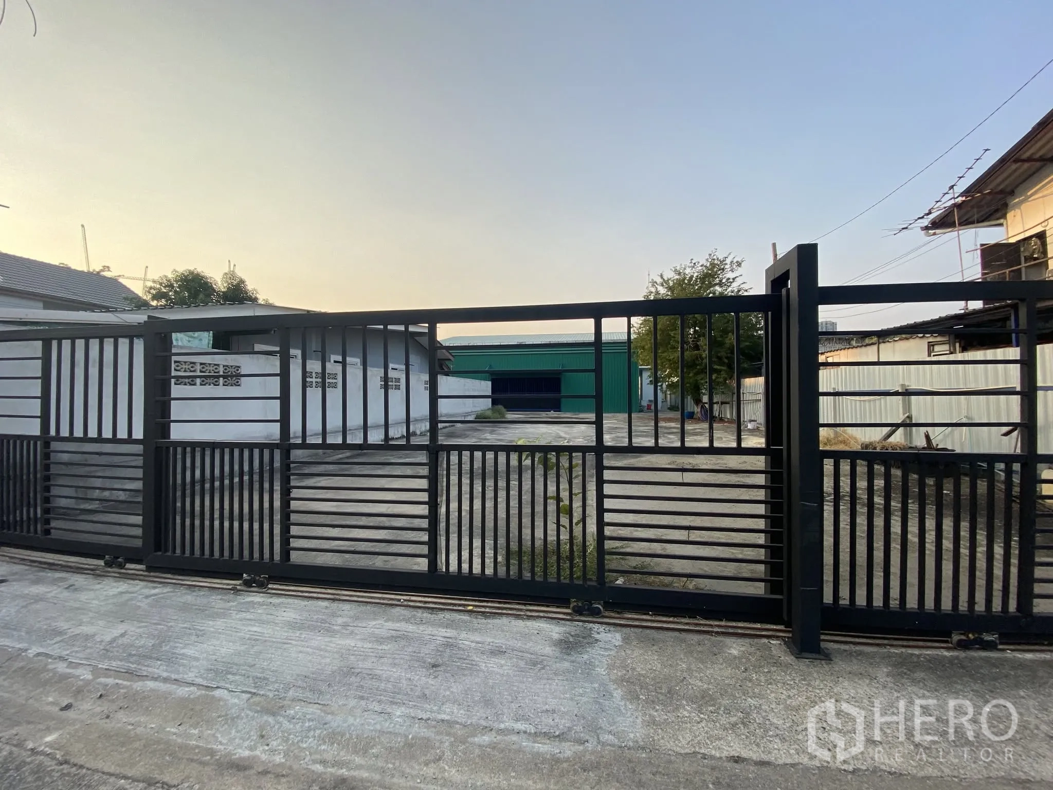 โกดัง for rent in Bang Na, Bangkok - ประตูรั้วบานเลื่อนด้านหน้าเปิดสู่ลานโกดังปูคอนกรีต