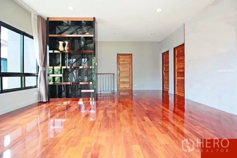 Detached House for rent in Bang Khae, Bangkok - Upper-floor family lounge with glossy teak wood flooring and custom shelving divider.