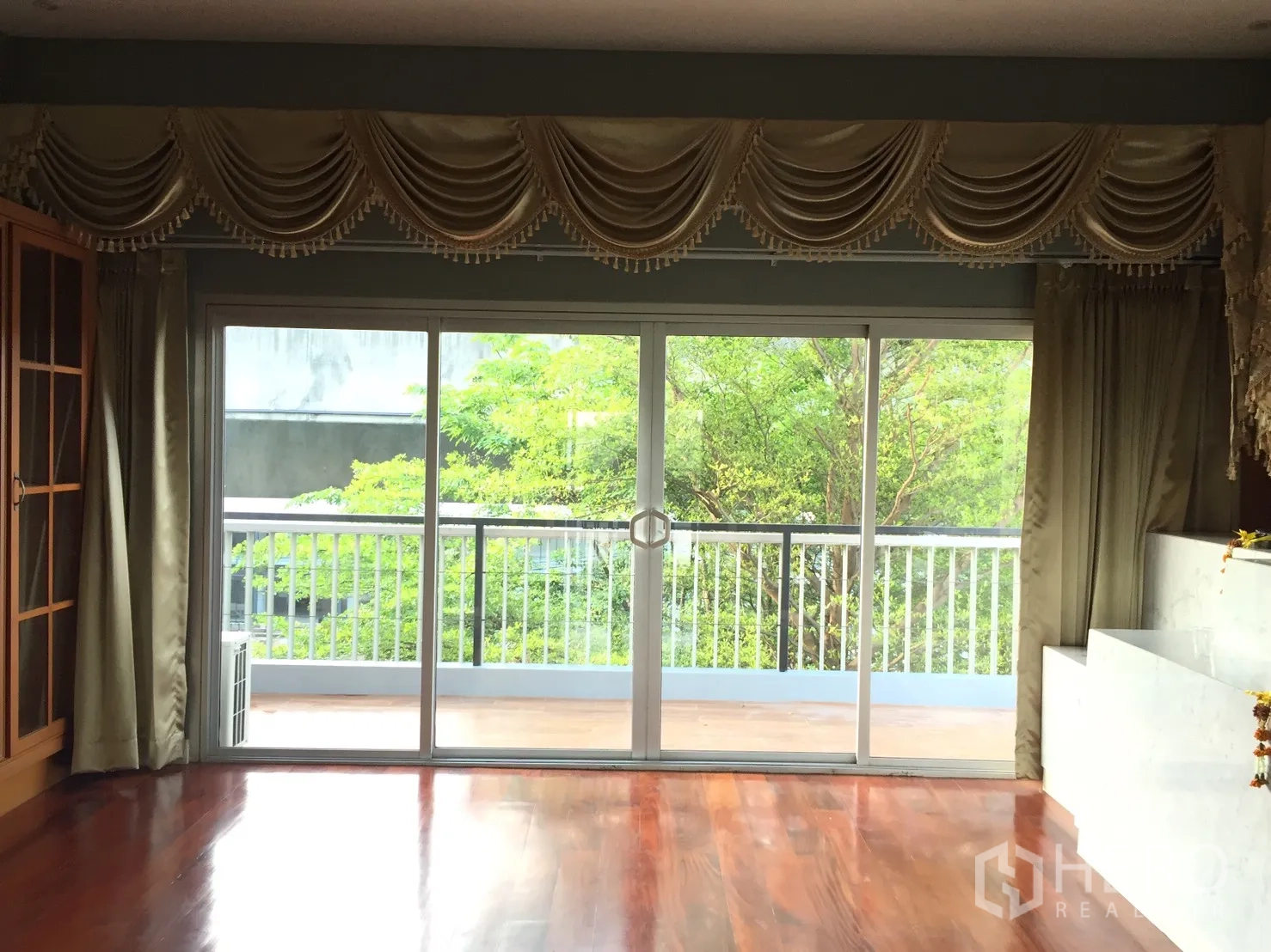 带办公室的家 出租或出售在Suan Luang, Bangkok - 客厅铺实木地板，推拉门通往露台与树景。