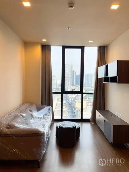 公寓 出售在Watthana, Bangkok - 客厅采光充足，落地窗与曼谷城市景观，配沙发与电视柜。