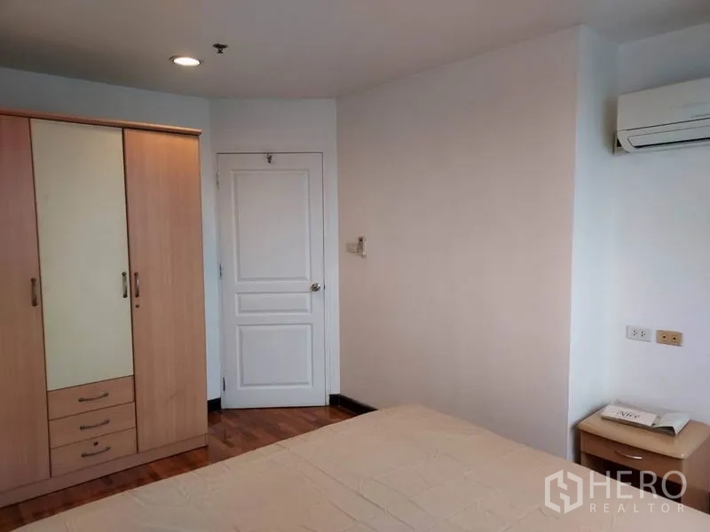 Condominium for rent or sale in Khlong Toei, Bangkok - Bedroom with wardrobe, air conditioning and wooden floors.