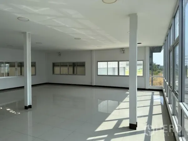 Warehouse for rent in Samut Prakan - Open-plan upper-floor office with columns, tiled floor, and wraparound windows.