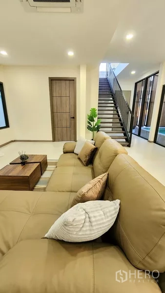 独立式住宅 出售在Khlong Toei, Bangkok - 沙发侧景，木门与玻璃墙旁的楼梯。