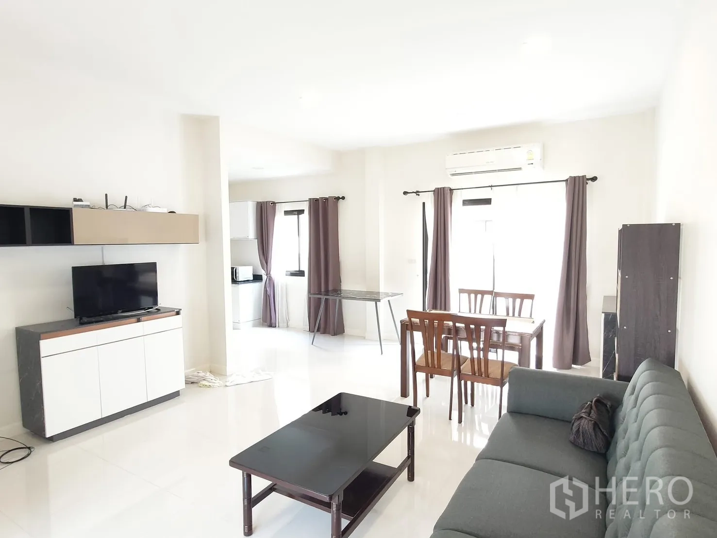 Townhouse for rent in Saphan Sung, Bangkok - Open-plan living and dining area with sofa, coffee table, TV console, table set and air conditioner.