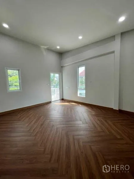 Townhouse for sale in Phra Khanong, Bangkok - Sunlit bedroom with herringbone flooring, multiple windows and a balcony door.