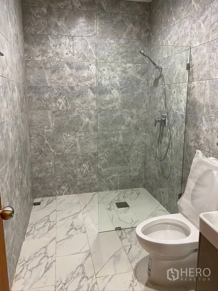 Detached House for rent in Suan Luang, Bangkok - Bathroom with gray stone-look walls, walk-in shower, and toilet.