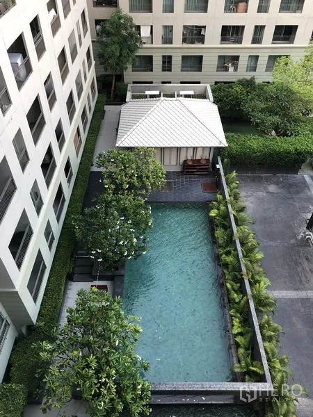 Condominium for rent in Pathum Wan, Bangkok - Courtyard swimming pool with pavilion, lush landscaping, and mid-rise buildings around.