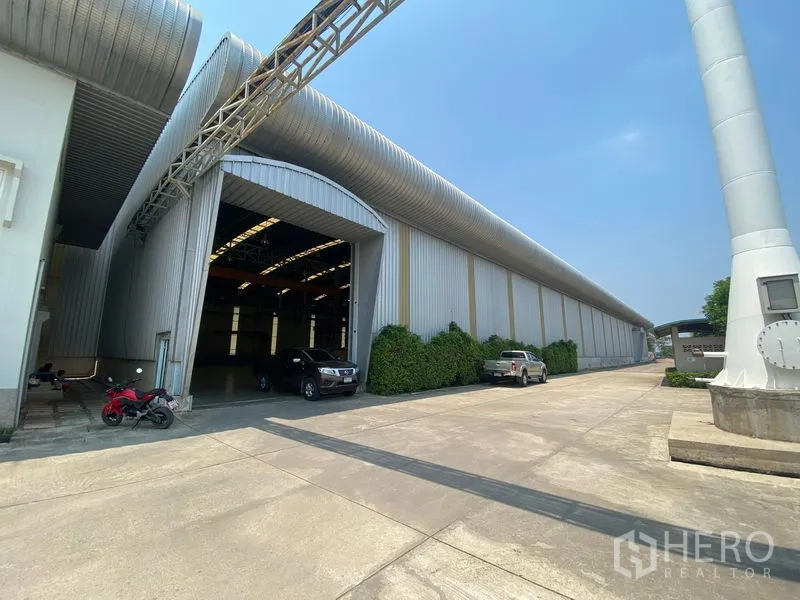 โรงงาน ให้เช่าหรือขายในSamut Sakhon - ภายนอกโรงงานที่บ้านแพ้ว สมุทรสาคร พร้อมลานคอนกรีตกว้าง ทางเข้าโหลดสินค้า และท่อระบายอากาศโลหะ.