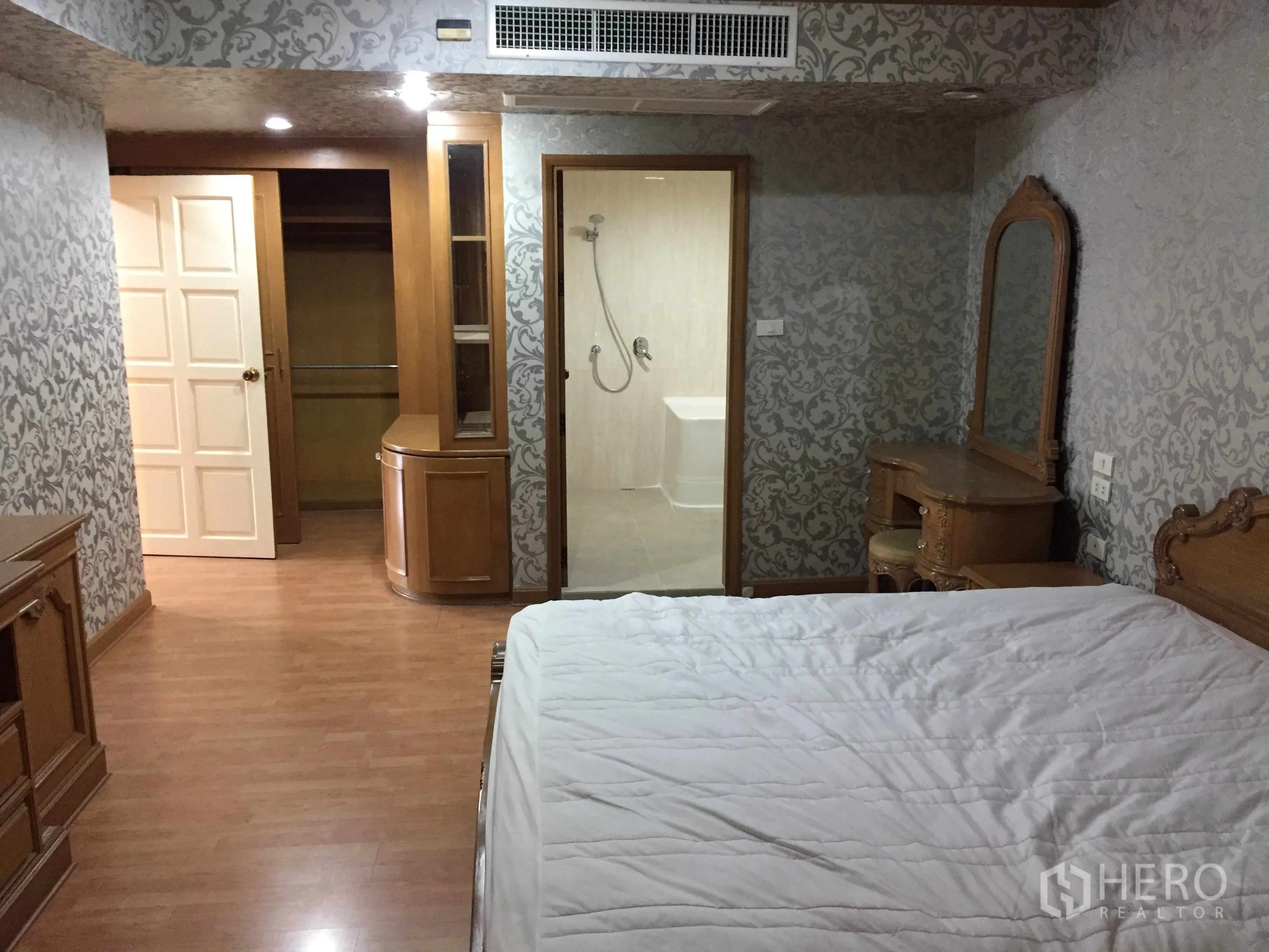 คอนโด ให้เช่าในWatthana, Bangkok - มุมห้องนอนใหญ่เชื่อมวอล์กอินโคลเซ็ตและห้องน้ำในตัว พร้อมโต๊ะเครื่องแป้งและงานไม้สไตล์คลาสสิก