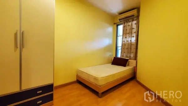 Condominium for rent in Khlong Toei, Bangkok - Secondary bedroom with single bed, wardrobe, window and wall-mounted air conditioner.