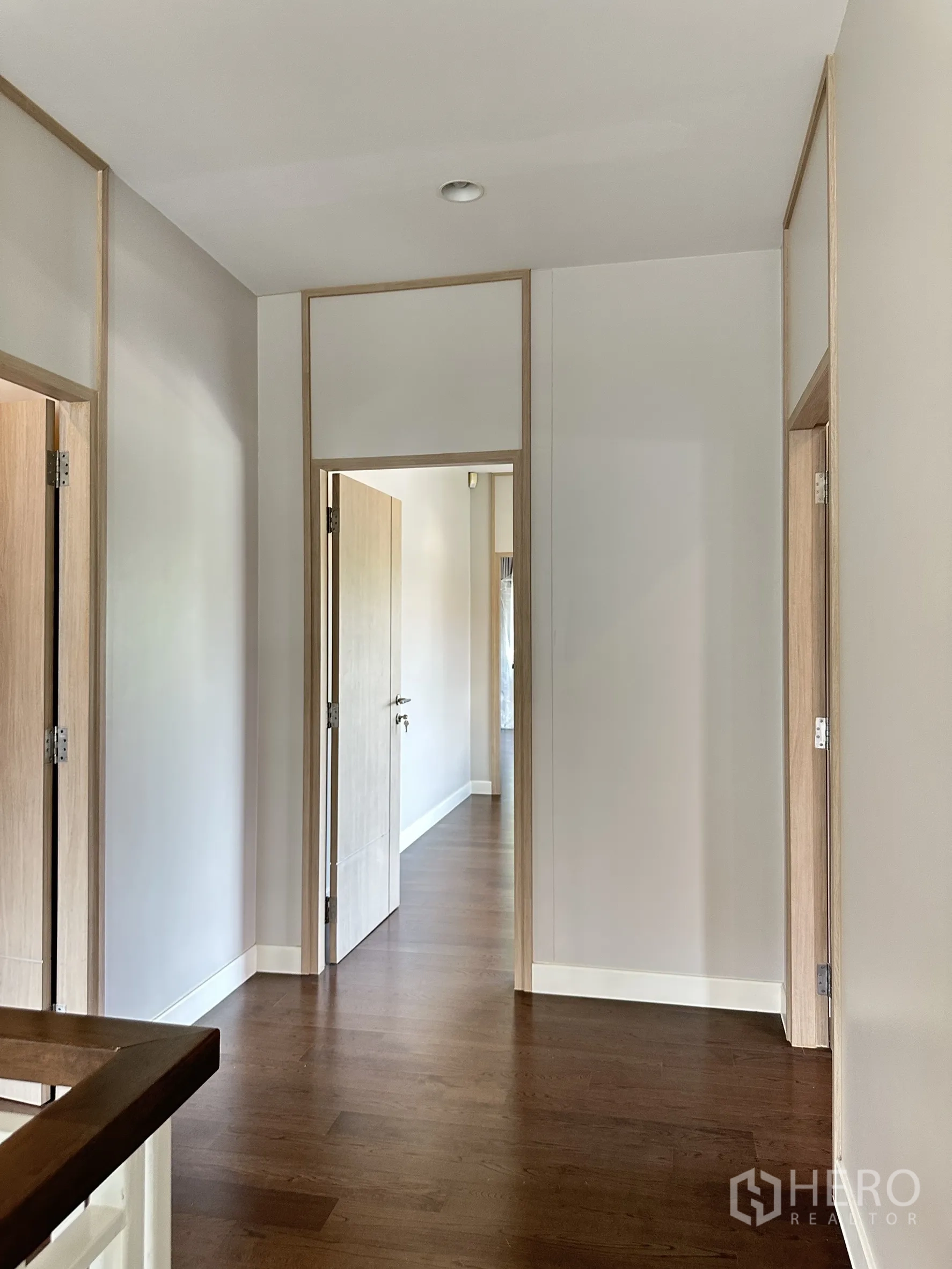 Detached House for sale in Lam Luk Ka, Pathum Thani - Upper hallway with wooden floors leading to multiple bedrooms.