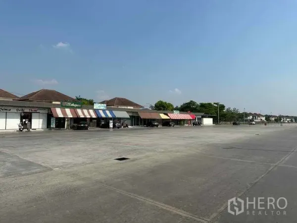 Retail Space for rent in Pathum Thani - Row of single-storey retail units with colorful awnings facing a large open parking area.