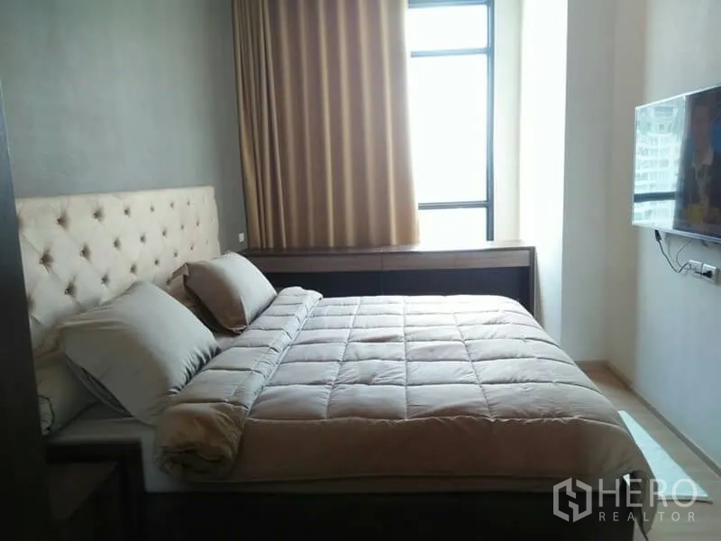 公寓 出租在Huai Khwang, Bangkok - 采光充足的主卧，落地窗、墙挂电视与软包床头。