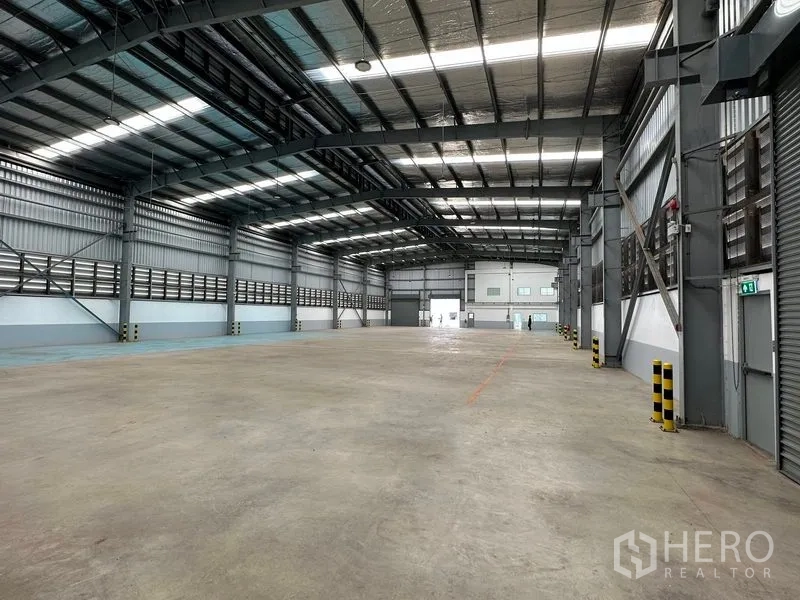 Factory for rent in Mueang Samut Prakan, Samut Prakan - Column-free warehouse space with ventilation panels and safety bollards along the walls.