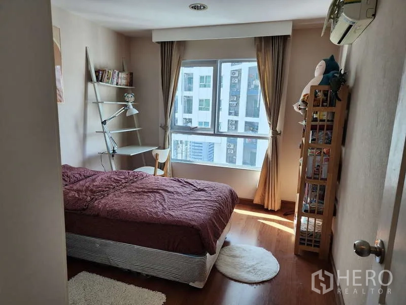 คอนโด ให้เช่าในHuai Khwang, Bangkok - ห้องนอนที่สองมีเตียง โต๊ะเขียนหนังสือ และชั้นวางของข้างหน้าต่างสว่าง