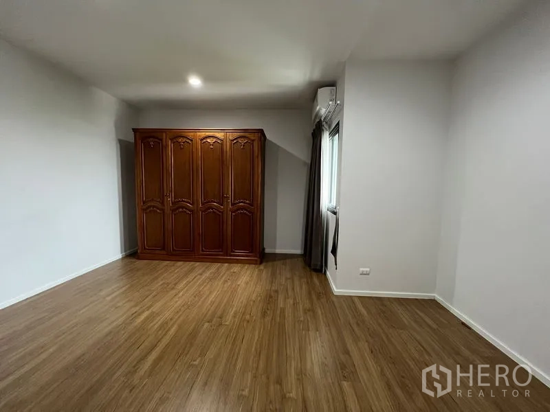 Detached House for rent in Saphan Sung, Bangkok - Spacious bedroom showcasing a classic wooden wardrobe and timber floors.