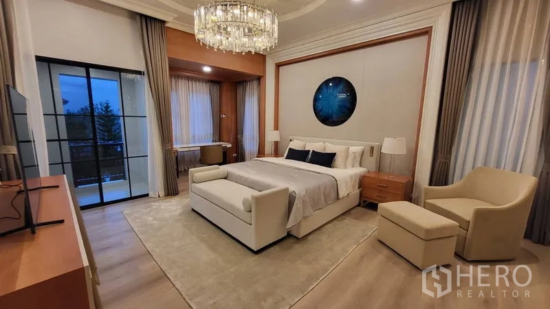Detached House for rent or sale in Saphan Sung, Bangkok - Primary bedroom with chandelier, sitting bench, and balcony behind black-framed doors.