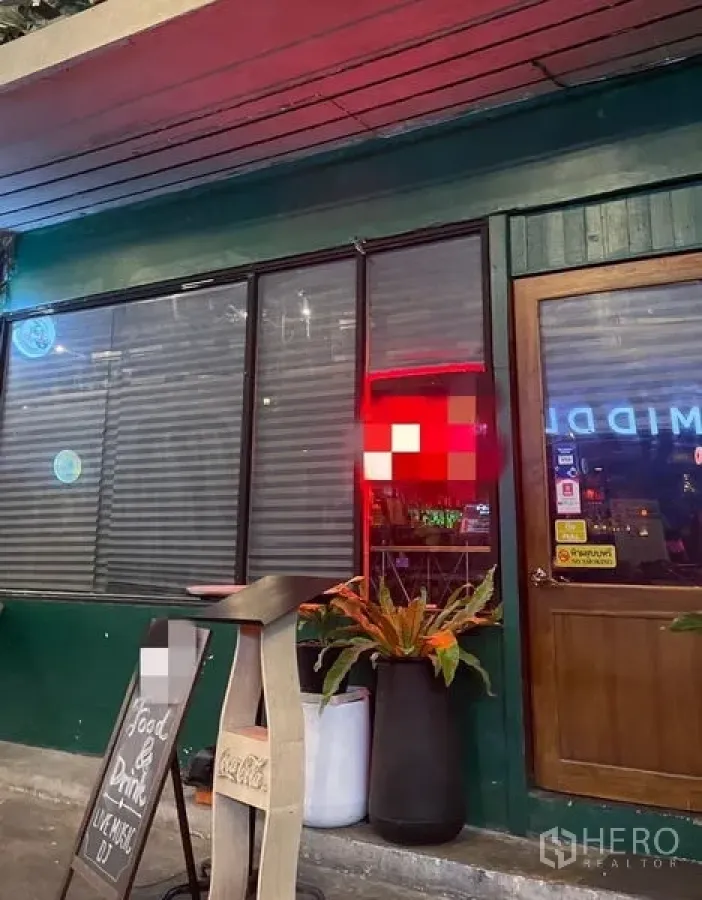 零售空间 出租 - 临街店面，绿色外立面，大面积玻璃与百叶窗、木门、黑板菜单与花盆。
