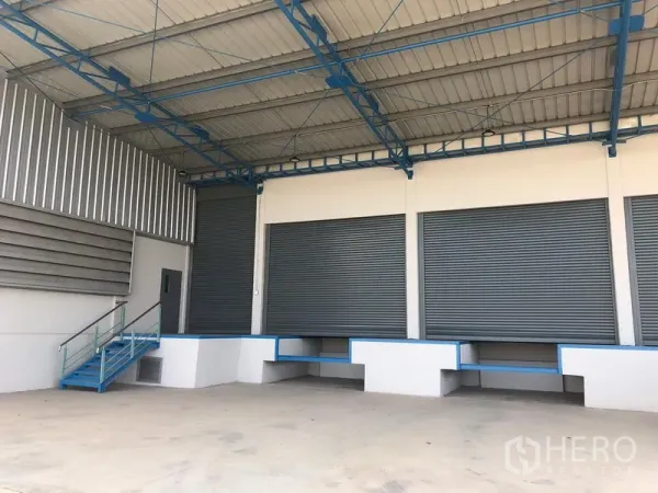 Warehouse for rent in Lat Krabang, Bangkok - Covered loading bay with multiple roller shutter doors and raised docks for truck access.
