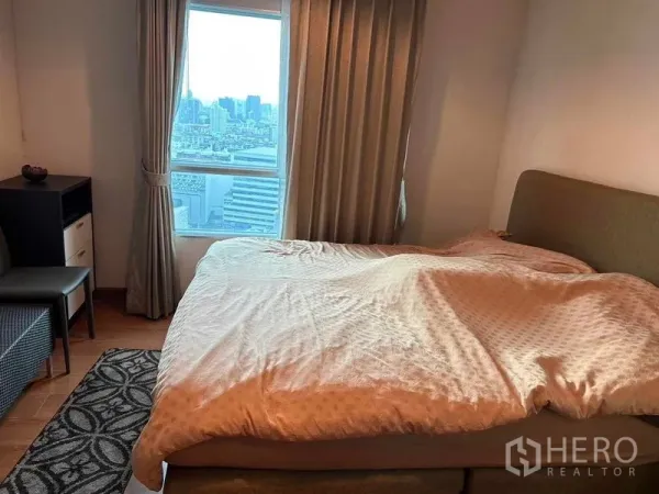คอนโด ขายในHuai Khwang, Bangkok - ห้องนอนเตียงขนาดใหญ่ ผ้าม่านสูงเต็มบาน พร้อมหน้าต่างเห็นวิวเมืองกรุงเทพฯ